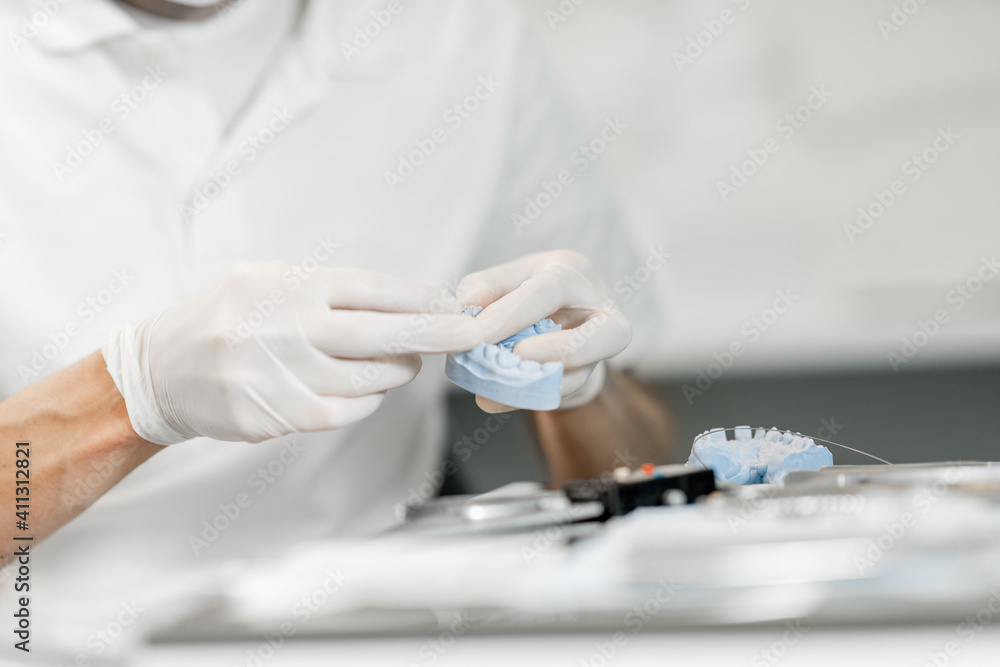 牙科技师与一个牙齿模型一起工作，尝试正畸治疗的支架系统a