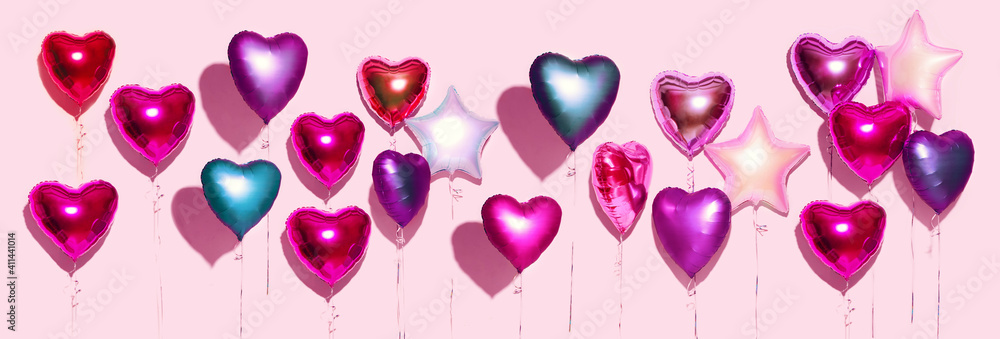 气球。粉红色背景上一束五颜六色的紫色、粉色、蓝色心形箔气球。Lo