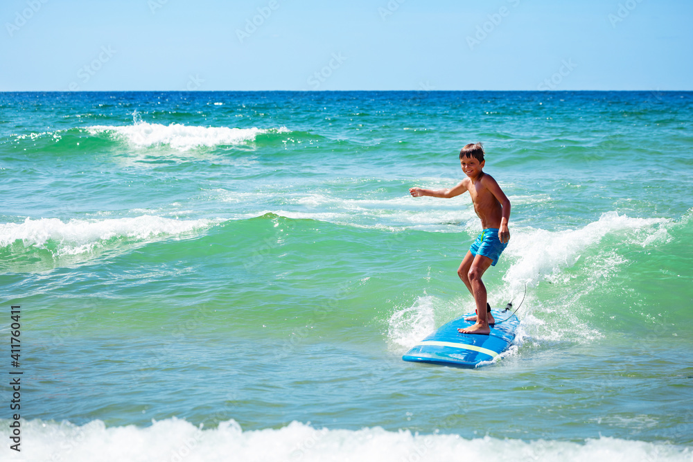 Young 10 years old boy action photo ride surfboard on a wave in the sea