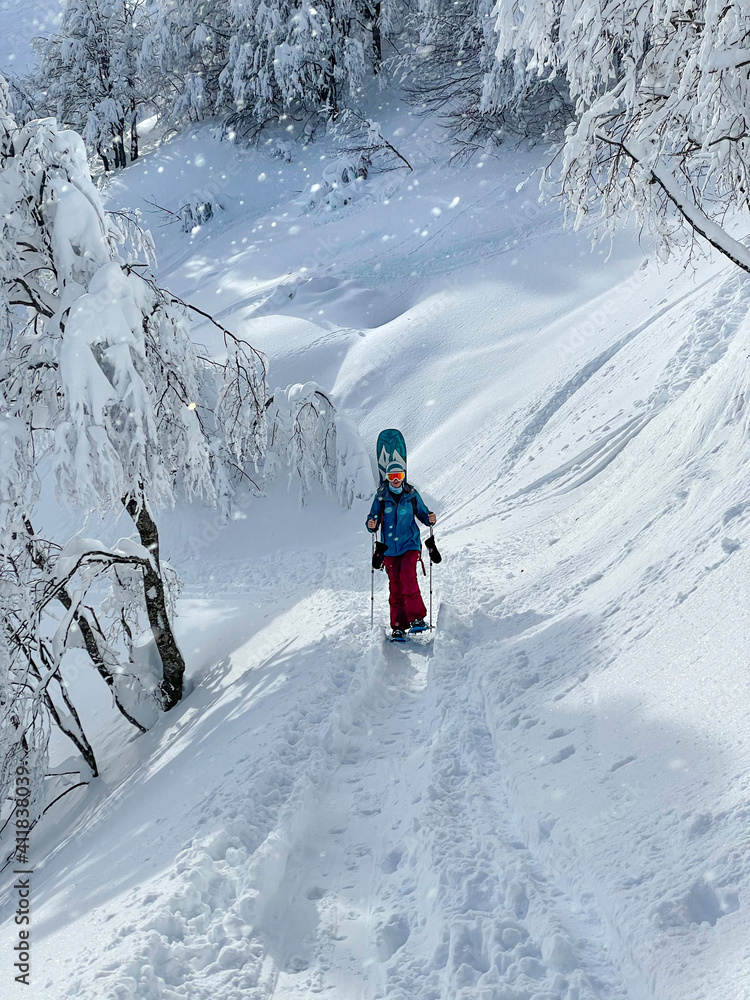 垂直：穿着滑雪板冒险雪鞋的健康女性登上山路。