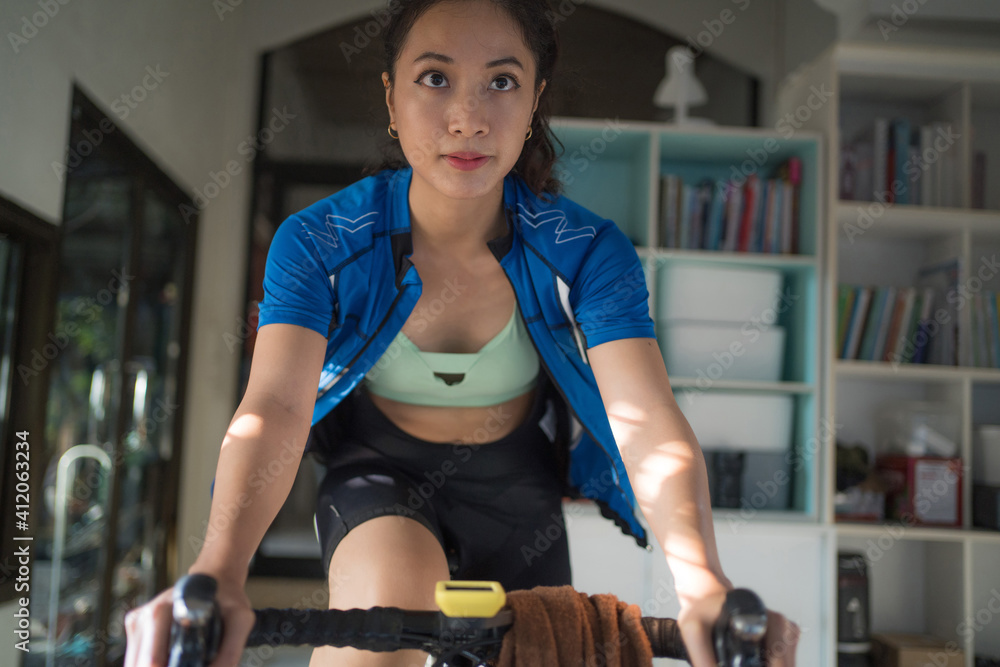 亚洲女自行车手。她在家锻炼。她在虚拟世界里玩游戏。