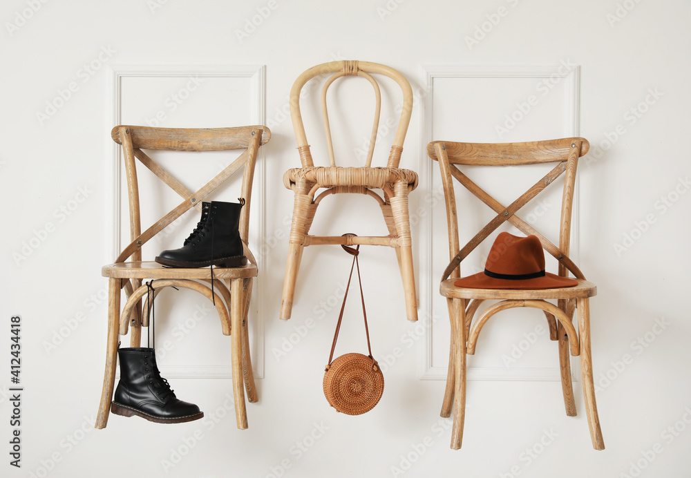 房间浅色墙上挂着鞋子和帽子的椅子