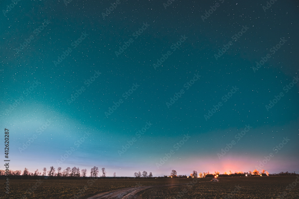 Night Starry Sky With Glowing Stars Above Country Road In Early Spring. Countryside Field Landscape