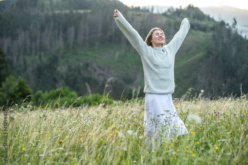 享受日落的快乐女人停留在山顶的绿草上。新鲜空气，特拉维