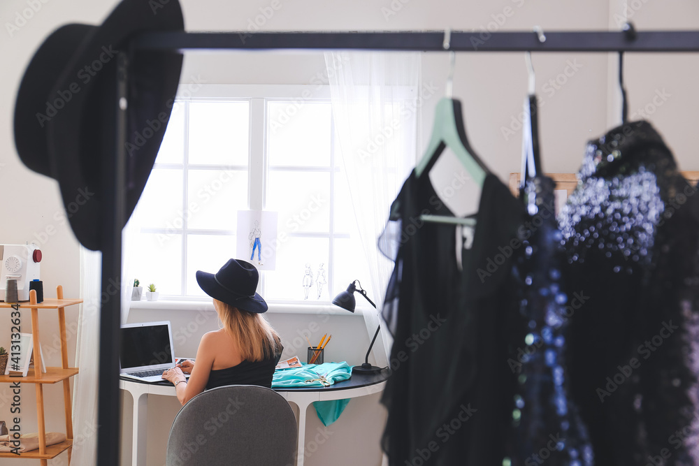 Female fashion designer with laptop working in studio