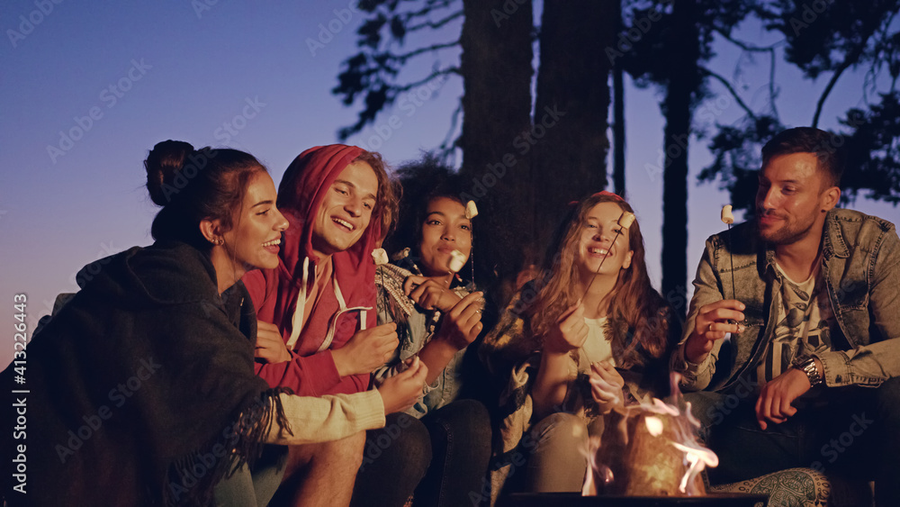 快乐的年轻露营者在森林中燃烧篝火，手持火花火芹菜