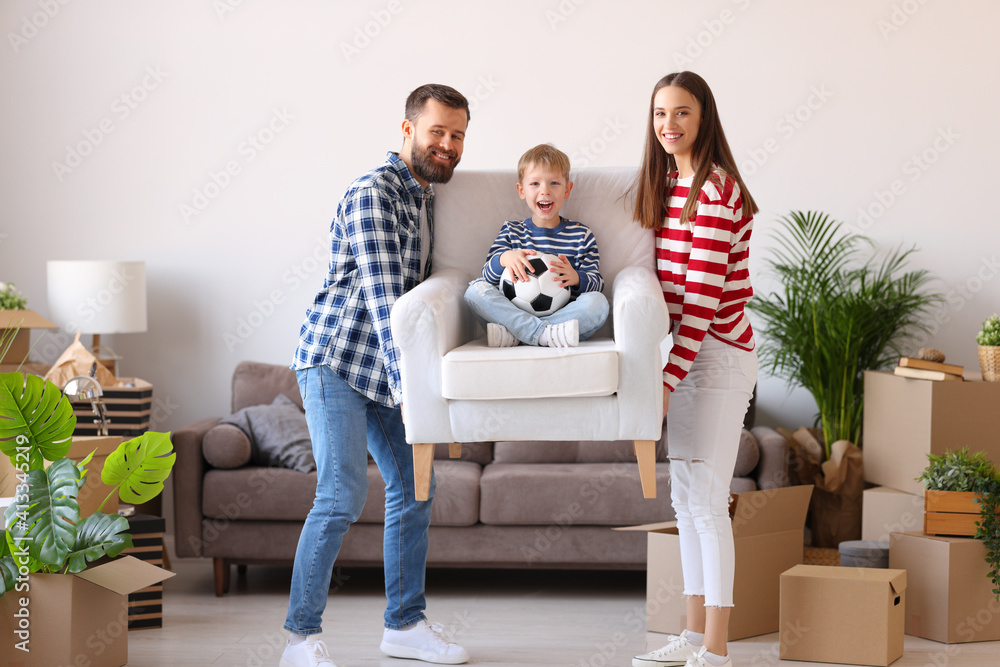Mother and father carrying armchair with son in new apartment