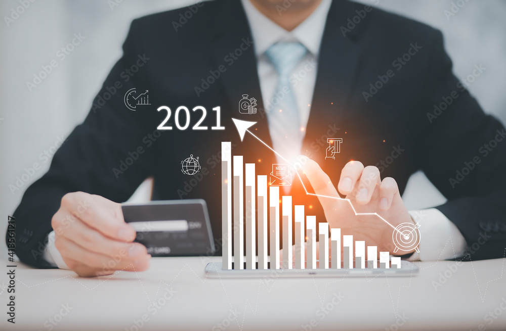 商人在笔记本电脑上持有信用卡并在互联网上绘制2021的触摸市场图，