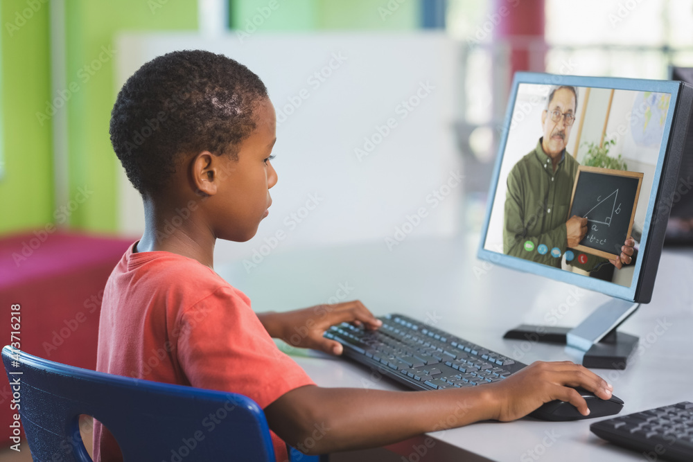 一名非裔美国男学生在学校与男老师进行电脑视频通话