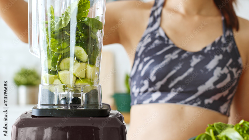 运动女性用搅拌机制作健康的绿色新鲜奶昔，用于健康饮料，包括蔬菜a