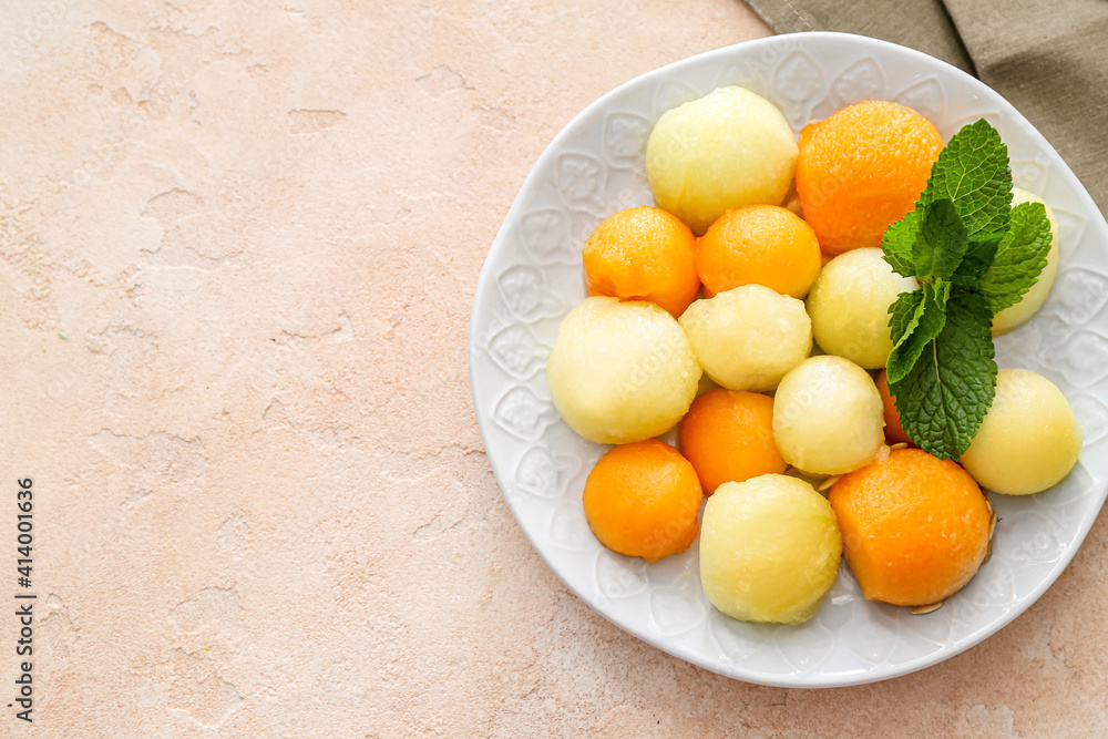 Plate with sweet melon balls on color background