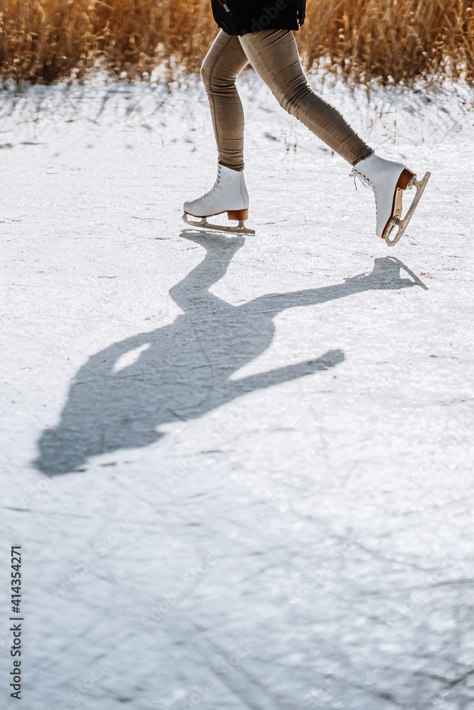 一个寒冷的冬日，年轻女子在池塘上滑冰。滑冰鞋的细节。