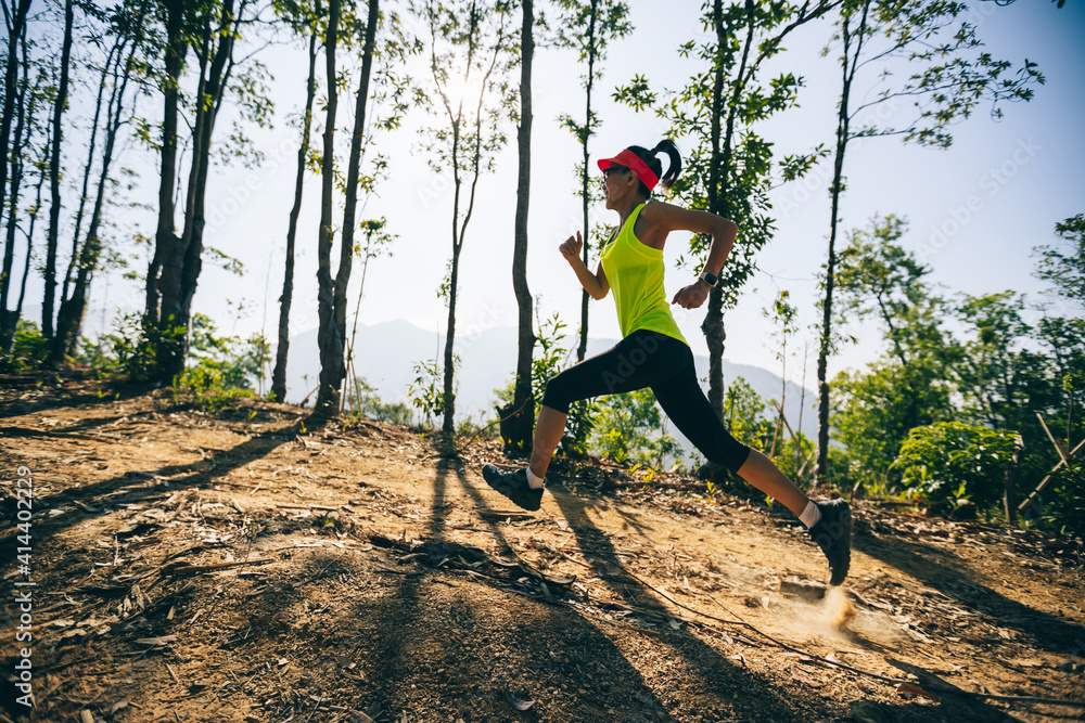 在日出的热带森林山峰上跑步的年轻女子跑步者