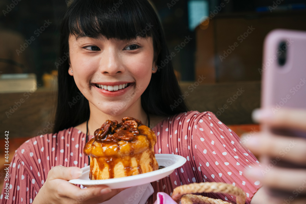 亚洲泰国长黑发女人在咖啡馆面包店与面包蛋糕自拍。
