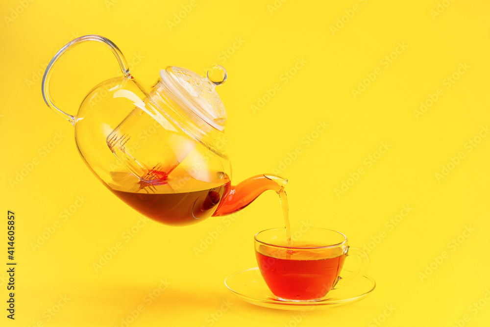 将茶壶中的热茶倒入彩色背景的杯子中
