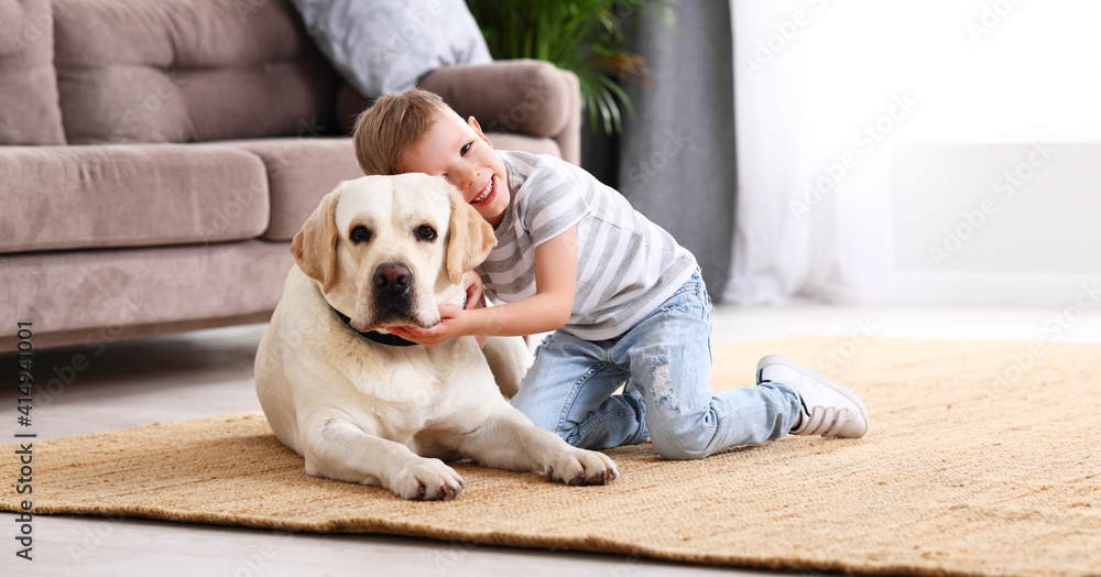 Little boy hugging dog at home