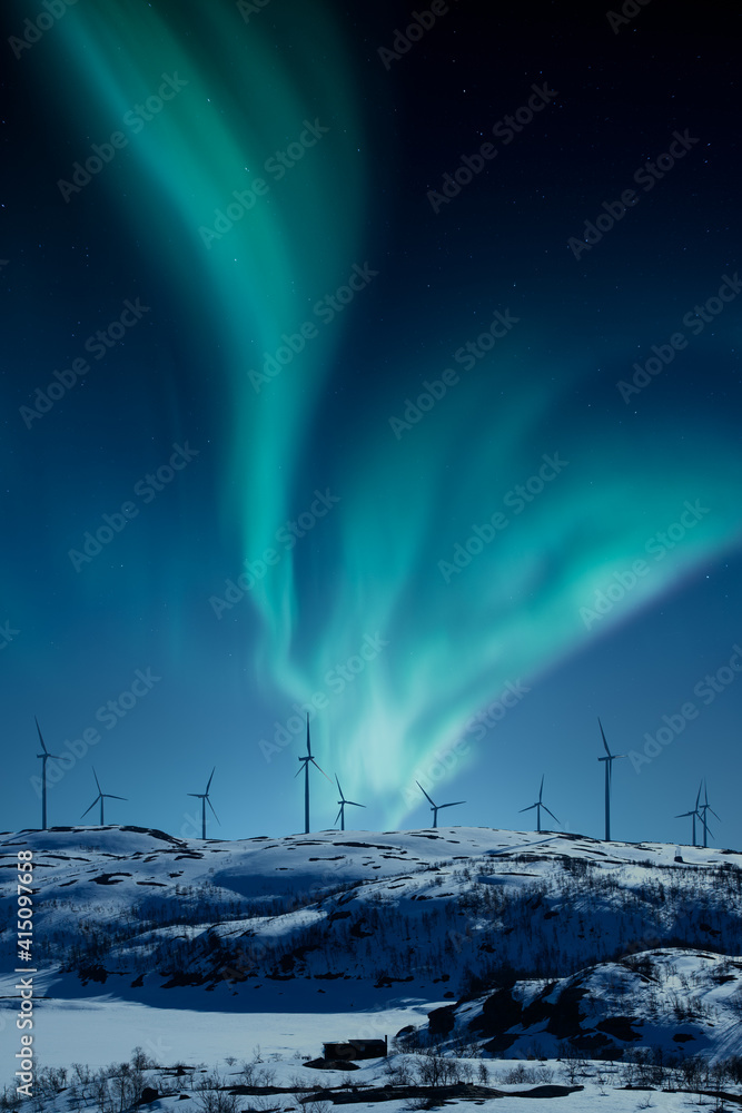 冬夜山丘上的风力发电厂，天空中有北极光