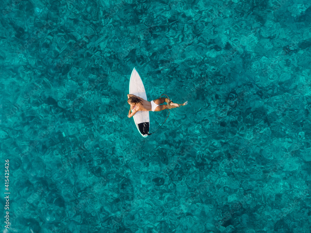迷人的冲浪女子在海洋中的冲浪板上放松。与冲浪女孩的鸟瞰图