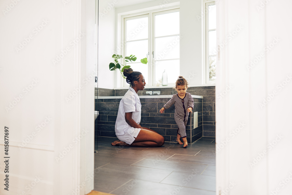 Young mom playing with her little girl in their bathroom