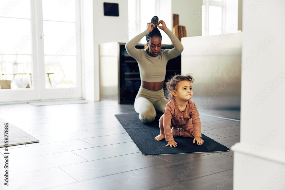 Mother and her cute little girl doing yoga at home