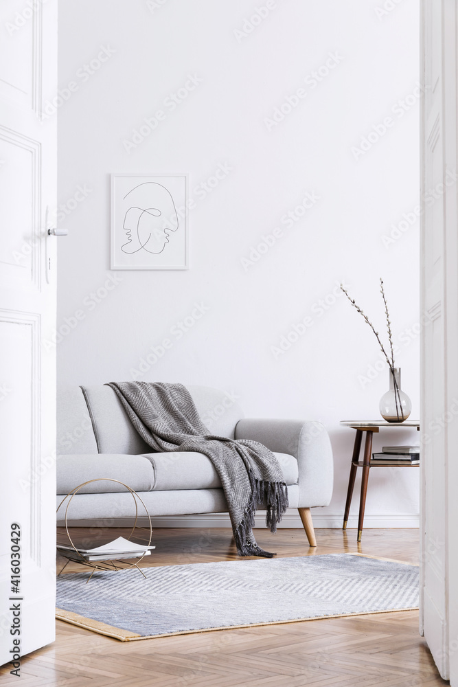 时尚的斯堪的纳维亚风格的客厅内部，配有设计灰色沙发、复古木桌、模型立柱