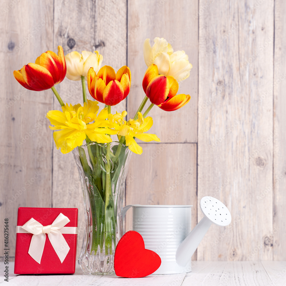 木桌和墙上的玻璃花瓶里放着母亲节问候用的郁金香。
