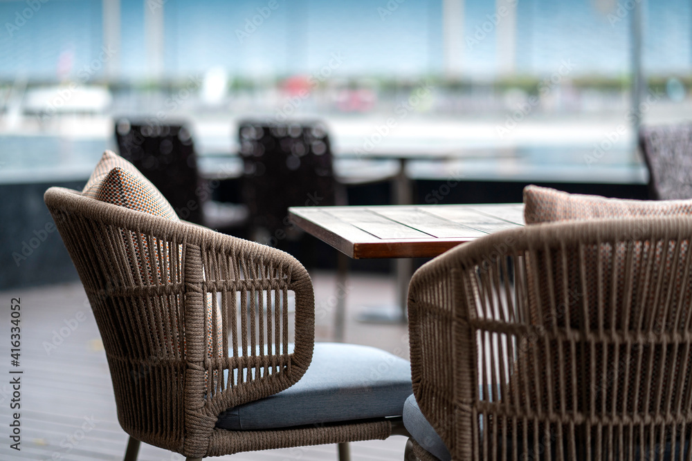 藤条柳条材料装饰咖啡馆露台的餐桌，模糊的户外花园背景int