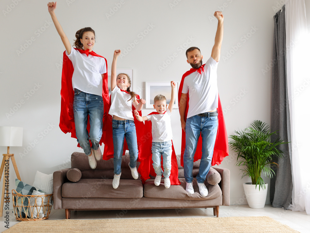 快乐的一家人穿着超级英雄服装从沙发上跳下来