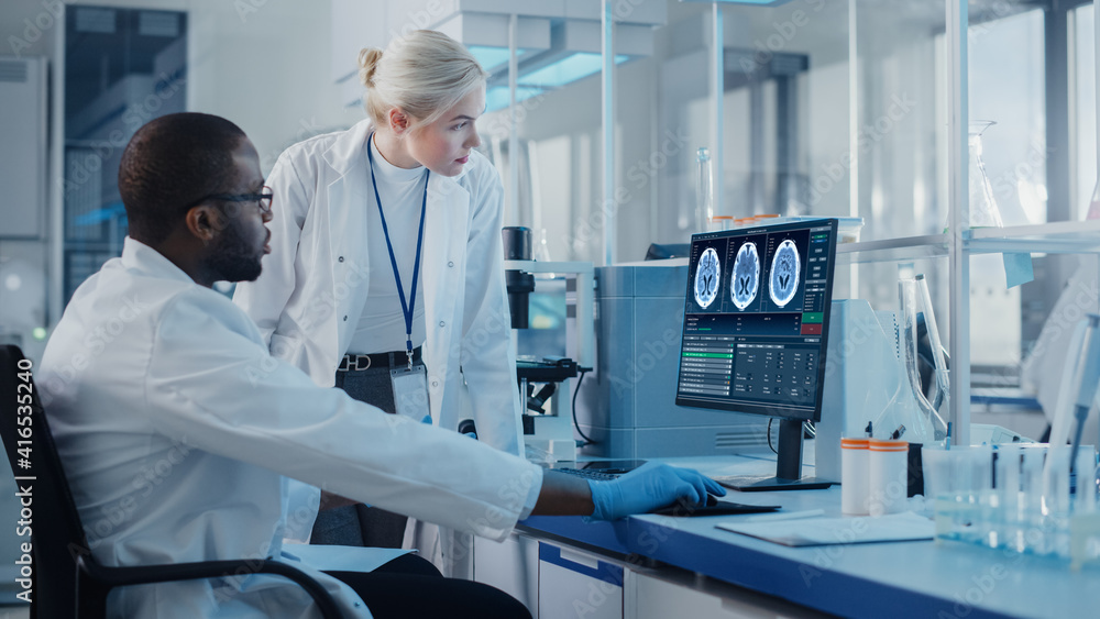 现代医学研究实验室：两名科学家使用屏幕显示MRI脑部扫描的计算机，