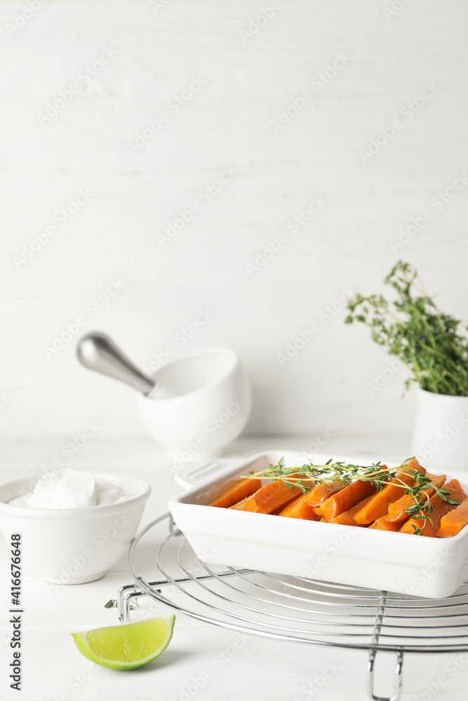 Dish of tasty baked carrot on light wooden background