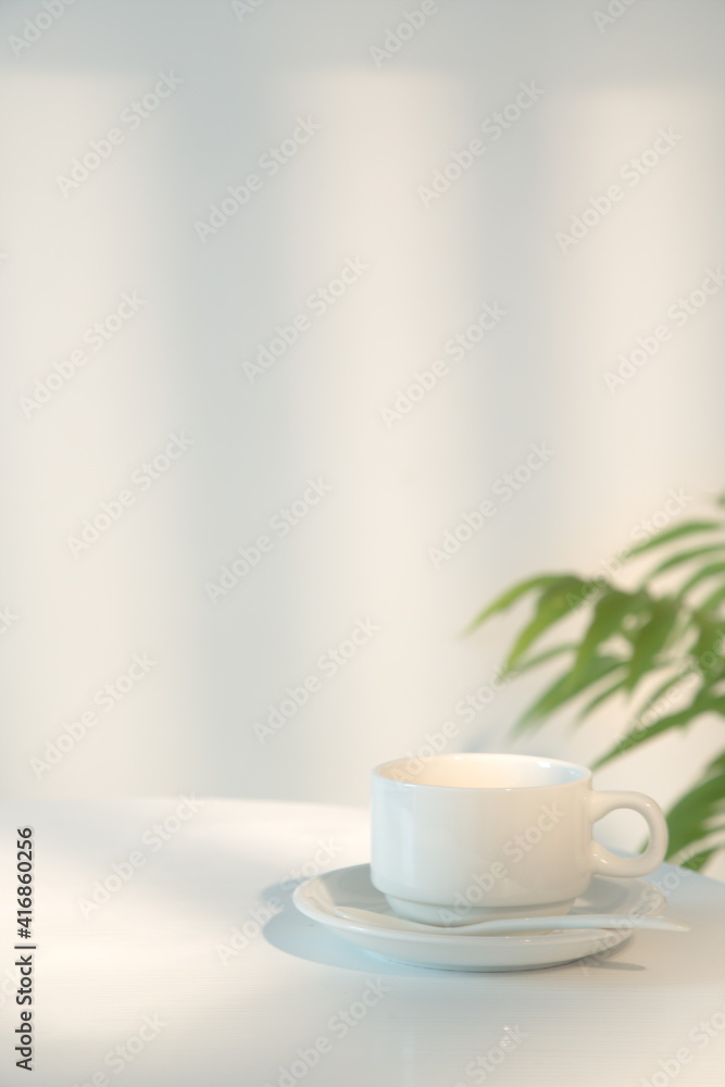 米色背景的桌子上放着一杯咖啡，清晨的阳光透过窗户照在上面