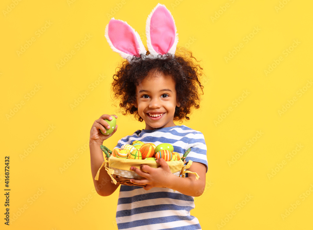 Cheerful ethnic kid holding Easter present in hands and laughing