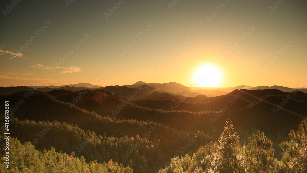 群山之上美丽的日落；橙色日落下的森林