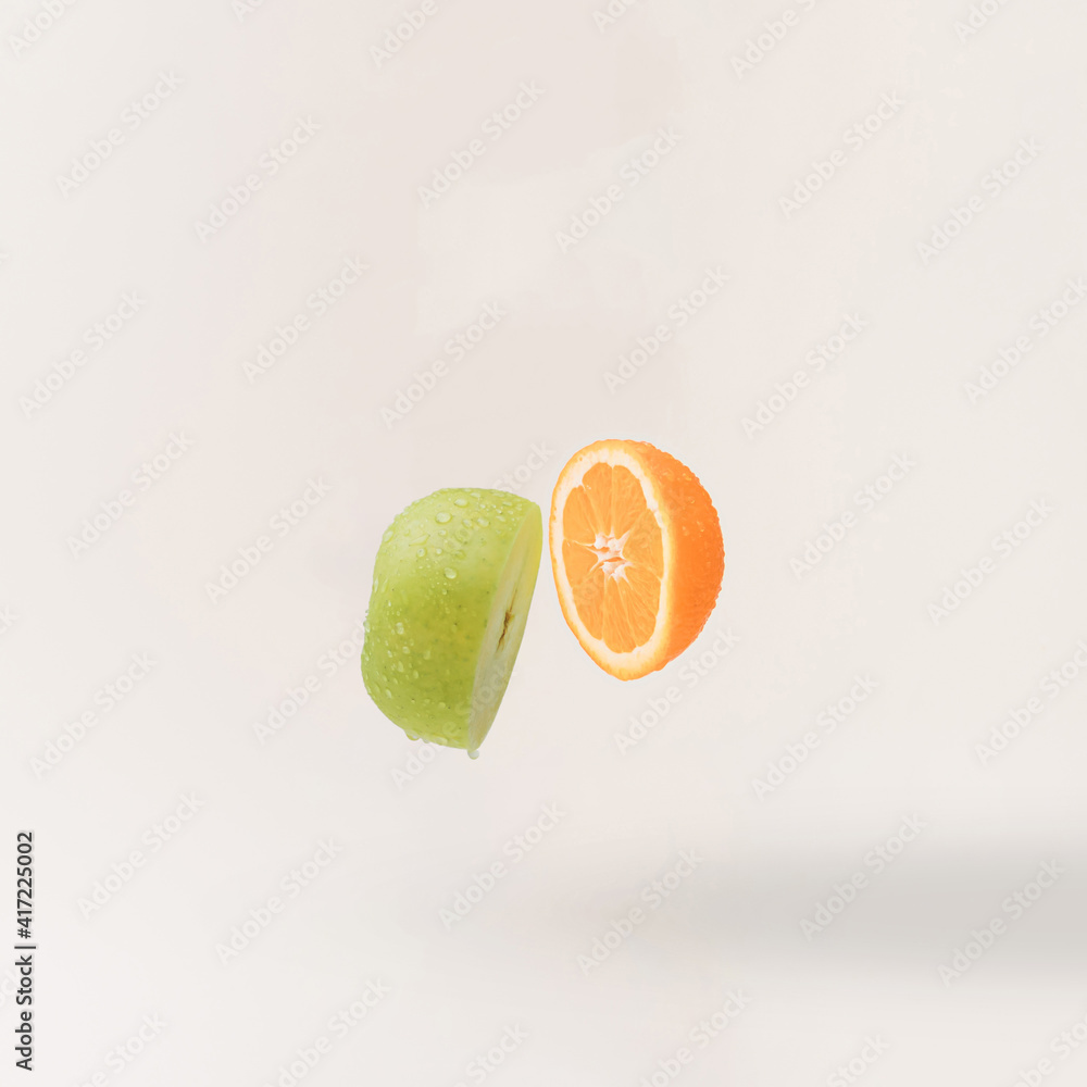 Sliced fresh green ​​apple and orange on beige background. Minimal concept.