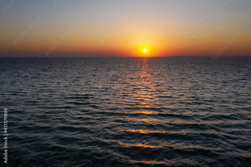 海洋中的日落，伴随着巨大的日暮柔和的海浪和红色多云的天空。海洋日出背景。陆地