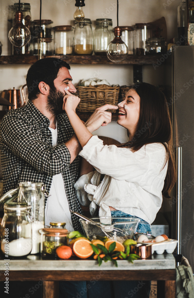 一对年轻幸福的夫妇在厨房里一起做饭，玩得很开心。积极的高加索男人和早午餐