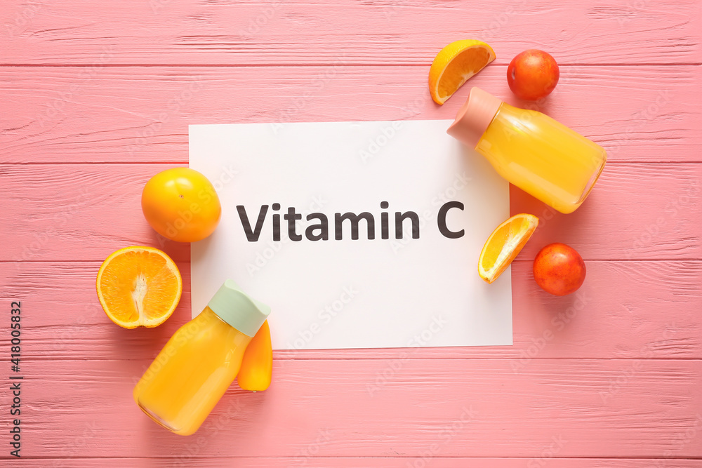 Healthy products, bottles of juice and text VITAMIN C on color wooden background