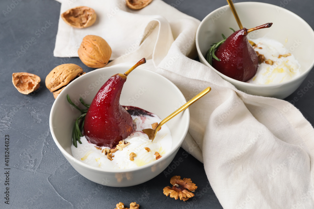 Bowls with sweet poached pears in red wine and ice-cream on dark background