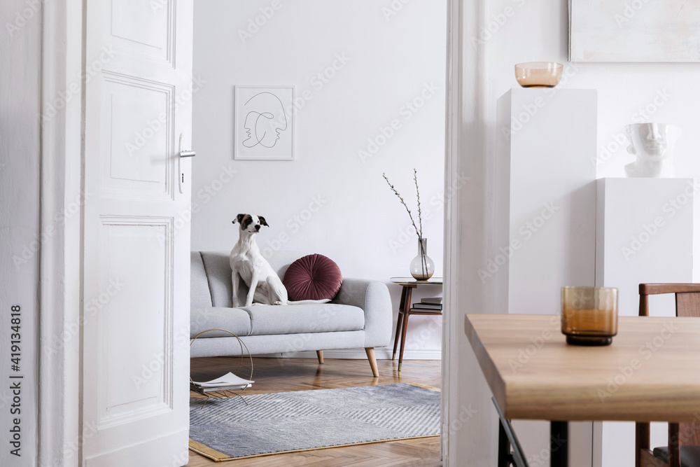 时尚的斯堪的纳维亚式客厅内部，配有设计木桌子、椅子、灰色沙发和装饰