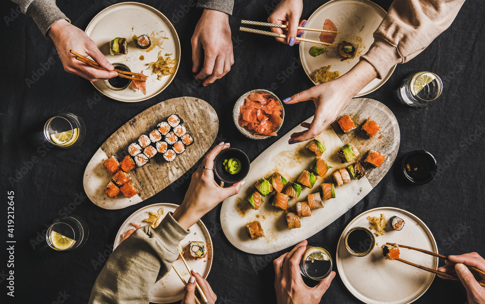 家庭将日本寿司晚餐从家中的送餐服务中锁定。餐桌上放着三文鱼。