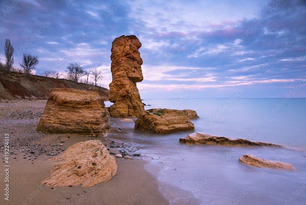 日落时海岸上有贝壳岩石的美丽海景。复活节的一尊巨石雕像