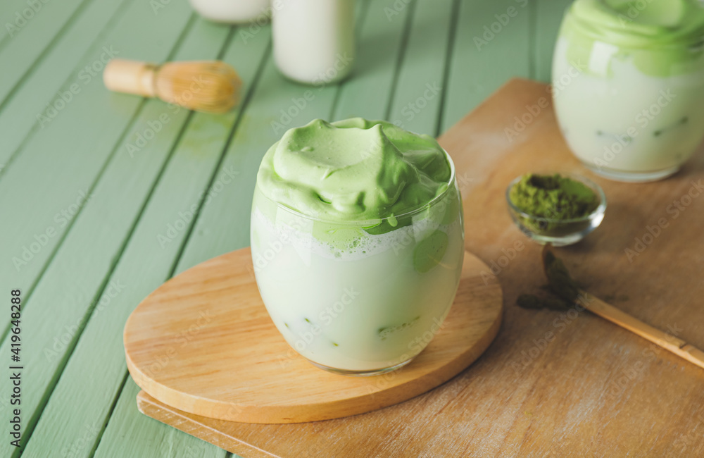 Composition with tasty dalgona matcha latte on color wooden background