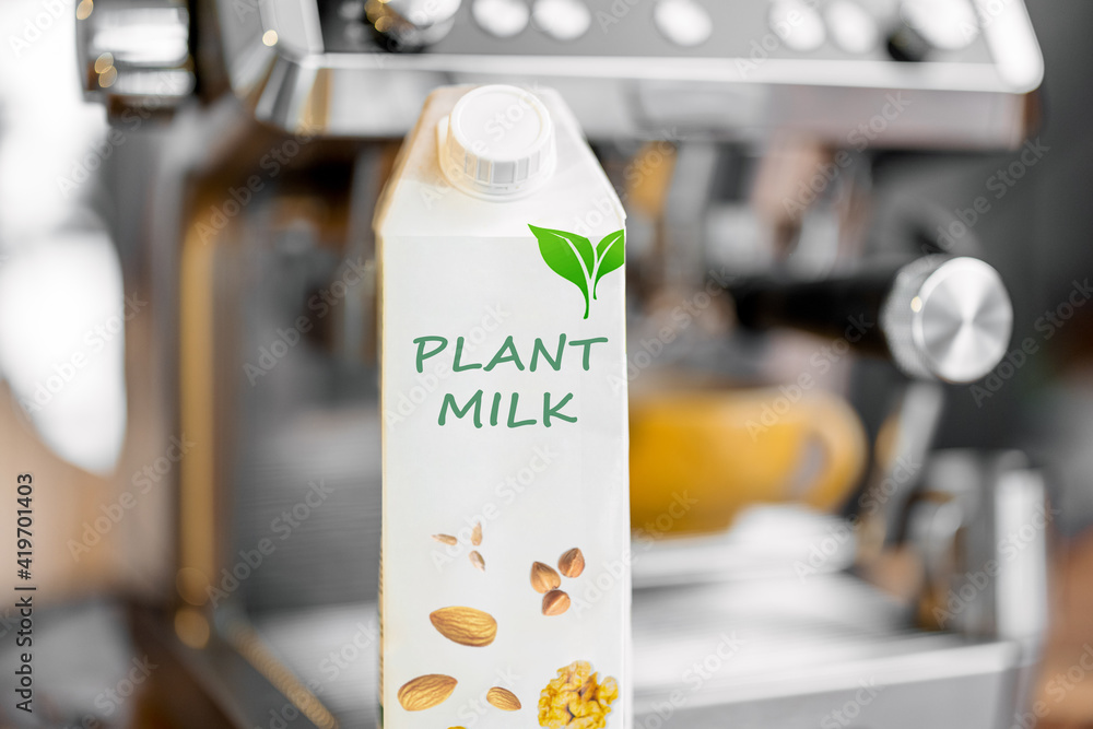 Packaging of vegetable milk near coffee machine. Organic nut dairy, alternative drink. Close up.