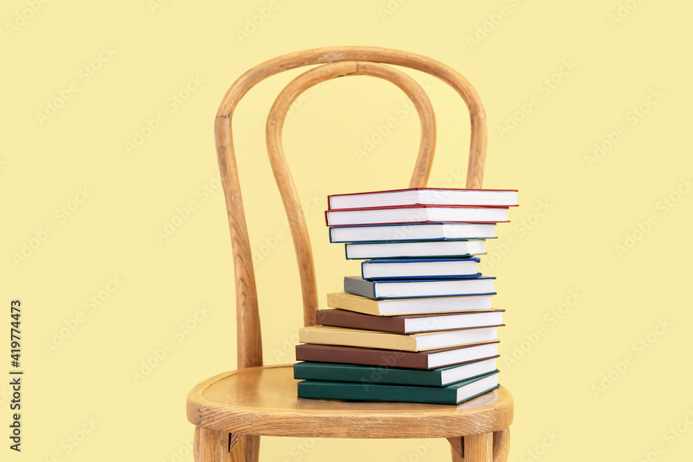 靠着彩色墙把一摞书放在椅子上