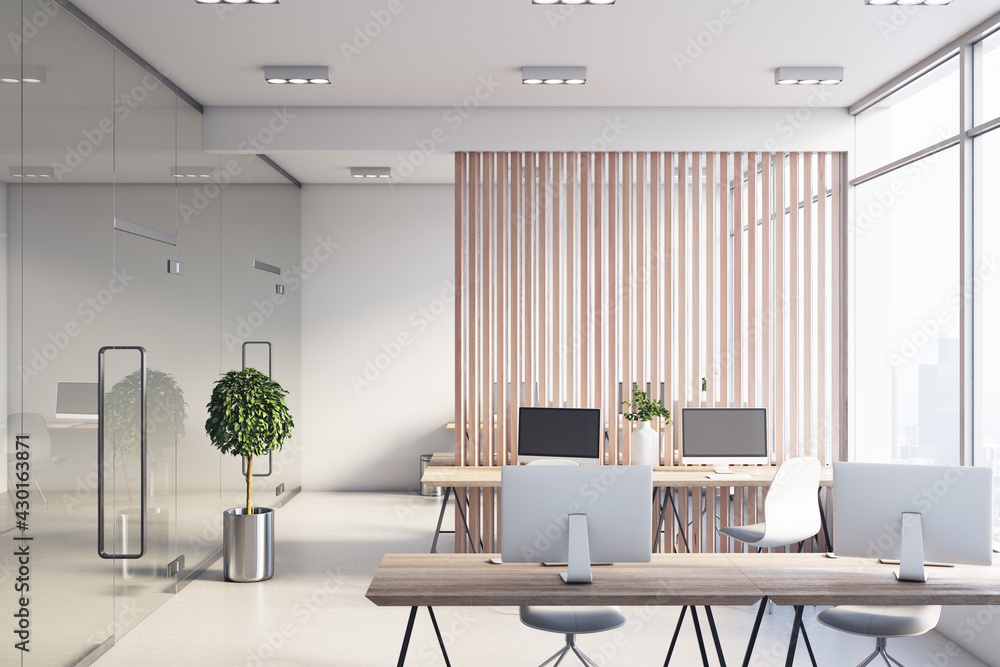阳光明媚、宽敞的办公室，时尚的工作场所之间有木板条隔断，现代化的显示器