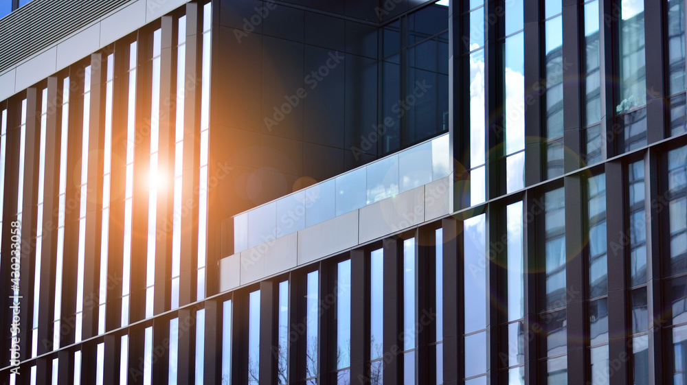 现代办公楼细节，玻璃表面以晴朗的天空为背景。的透明玻璃墙