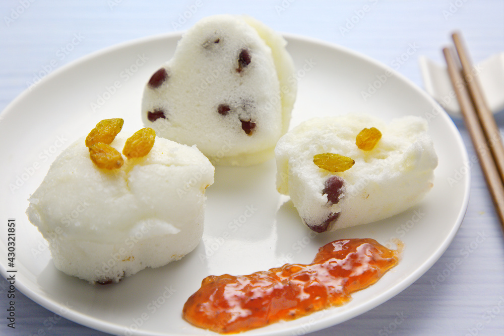 Three rice cakes with red dates and raisins, and sweet sauce in a white plate. Southern Chinese snac