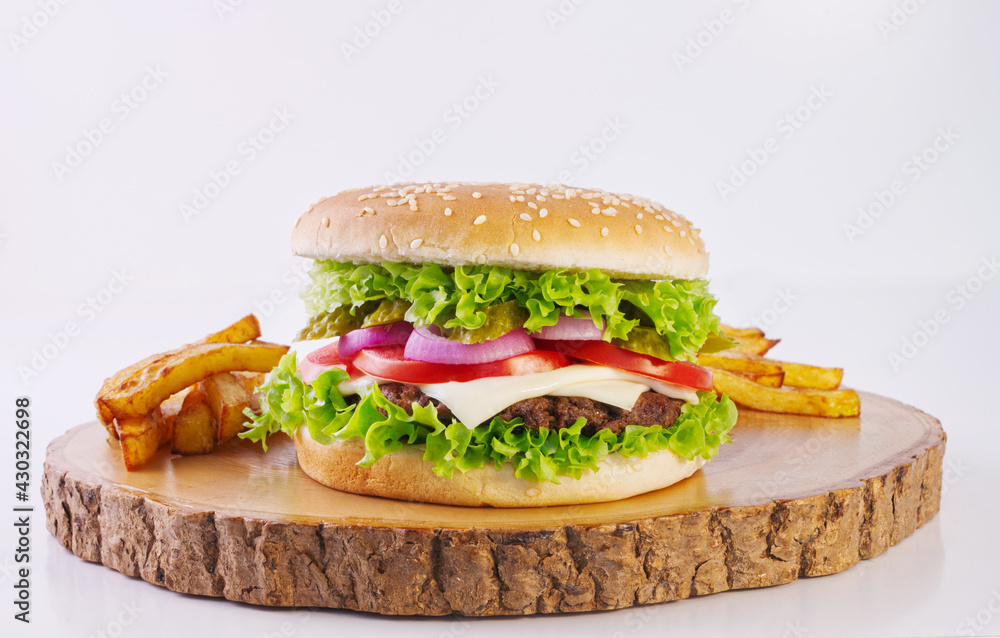 Hamburger with cheese and pickles, french fries on wooden cutting board, delicious fast food, white 