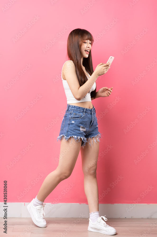 粉色背景下年轻亚洲女孩的全身形象