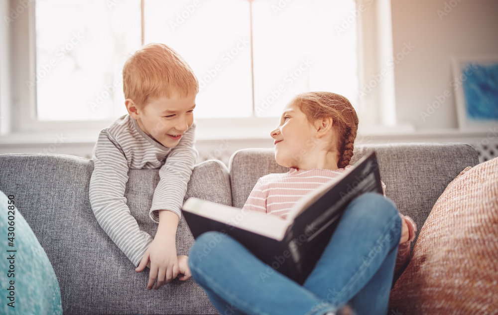 可爱的孩子坐在柔软的沙发上看书